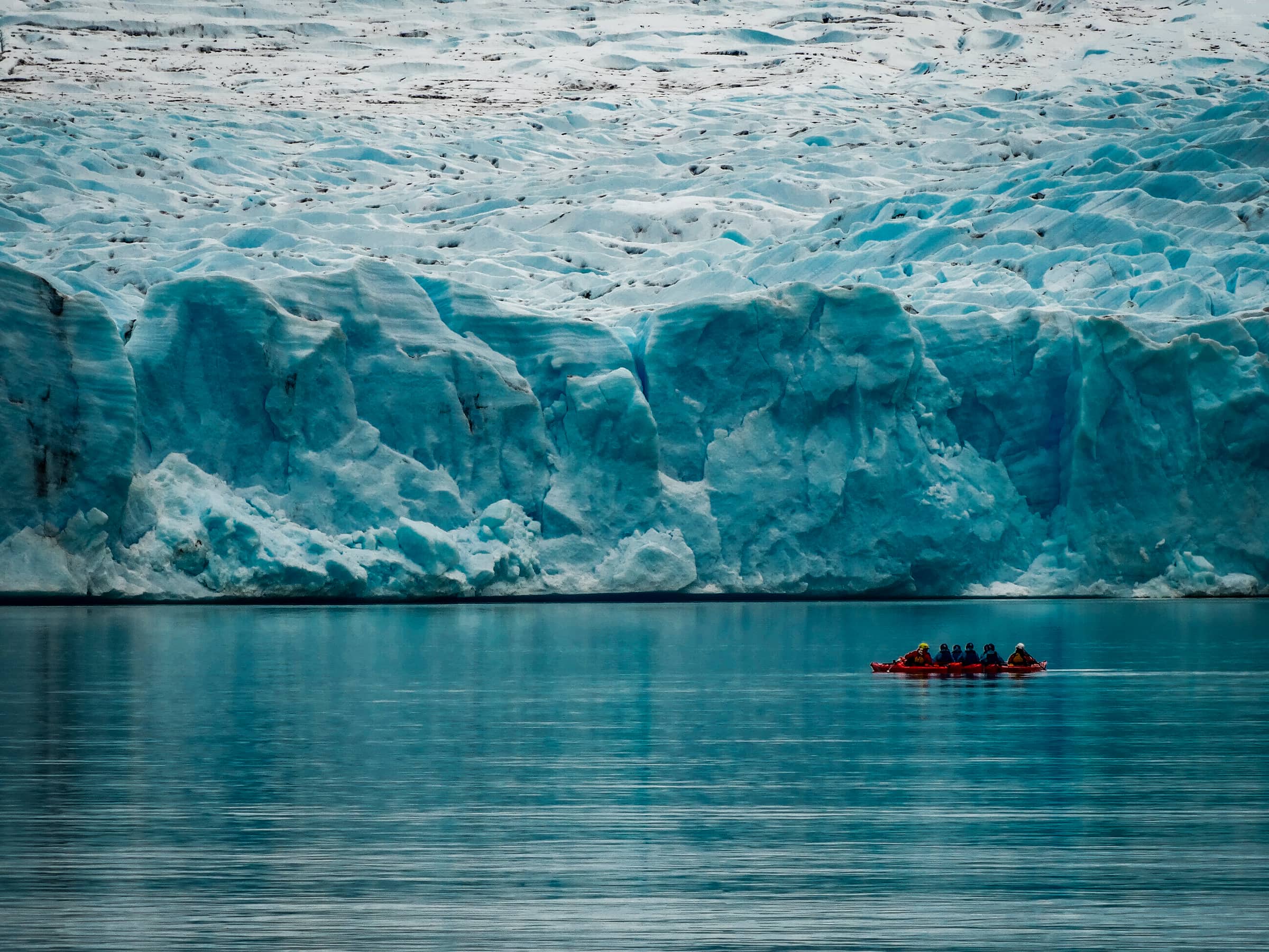 Grey Glacier in Chilean Patagonia. A wall of blue ice above still water, with kayaks alongside for scale.